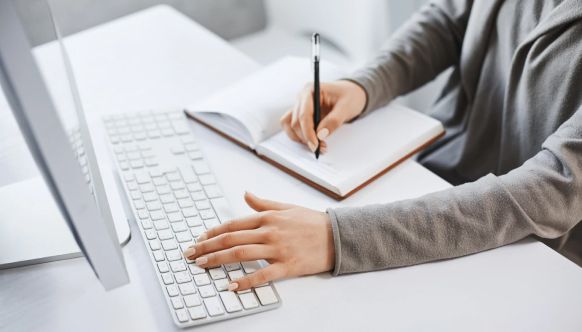 Woman typing on laptop and writing on laptop